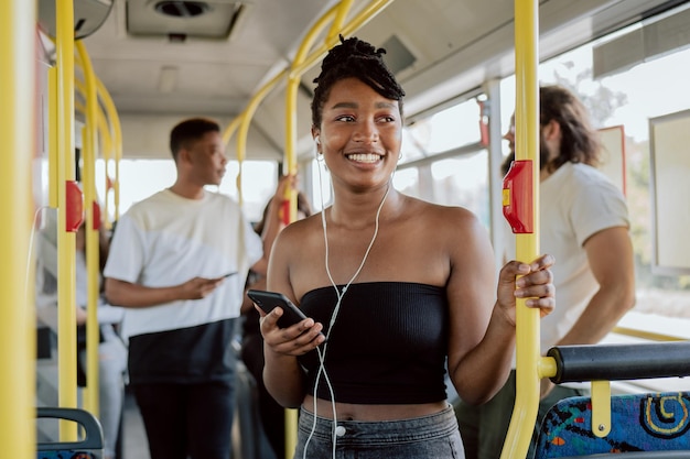 La donna sorridente di buon umore va in autobus a scuola al mattino con le cuffie nelle orecchie ascoltando musica