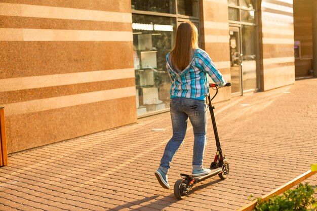 La donna sorridente è in piedi su uno scooter in città