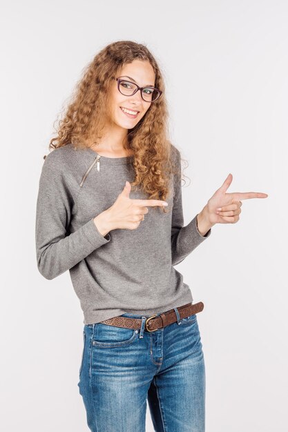 La donna sorridente mostra qualcosa sullo stile di vita del fondo bianco e sul concetto della gente