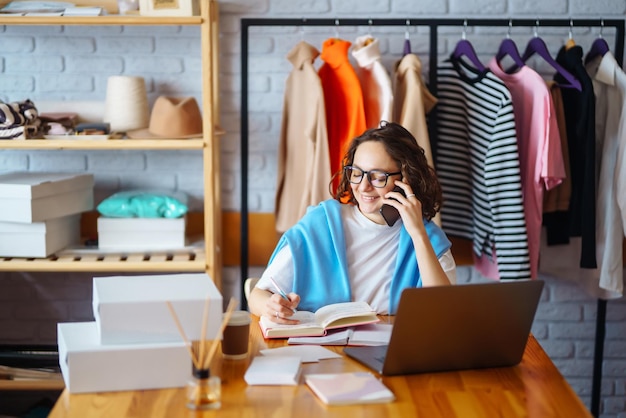 La donna sorridente prende appunti sugli ordini con il laptop Il proprietario di Dropshipping lavora