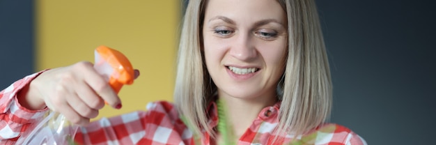 La donna sorridente si prende cura del fiore domestico in vaso di fiori. Concetto di piante domestiche