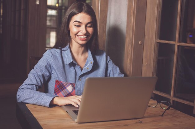 La donna sorridente sta lavorando con il computer portatile