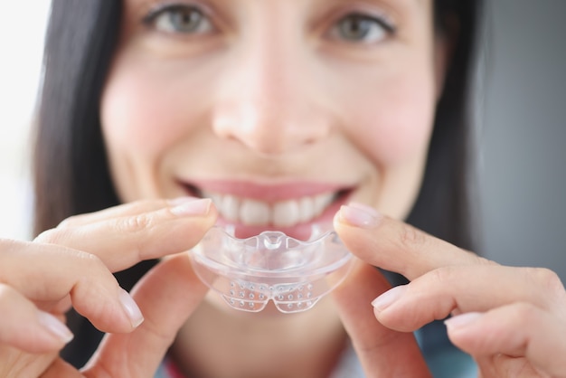 La donna sorridente tiene il paradenti di plastica trasparente per raddrizzare i denti