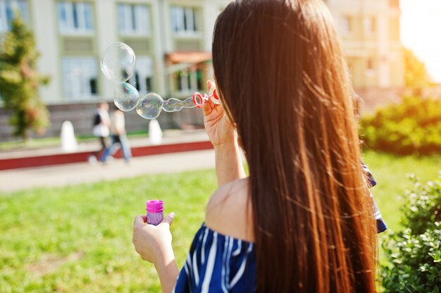 La donna splendida del brunette alla via della città fa uscire le bolle di sapone.