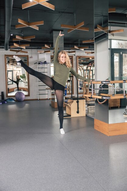 La donna sportiva sta facendo esercizi di stretching in studio moderno