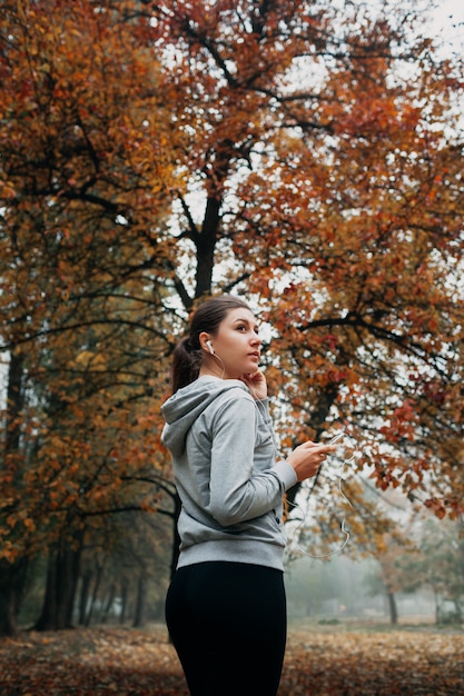 La donna sta accendendo la musica per correre nella foresta