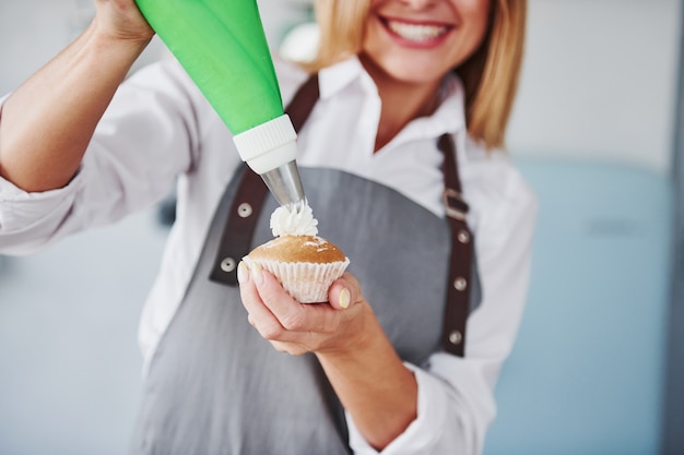 La donna sta al chiuso in cucina con torta fatta in casa.