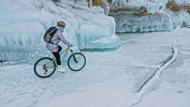 La donna sta andando in bicicletta sul ghiaccio La ragazza è vestita con uno zaino da ciclismo con piumino argentato