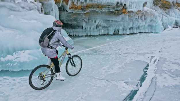 La donna sta andando in bicicletta vicino alla grotta di ghiaccio La roccia con il ghiaccio c