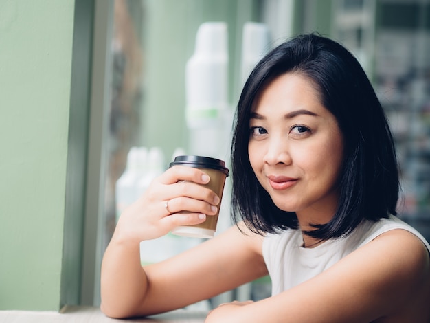 La donna sta bevendo una tazza di caffè caldo nel caffè.