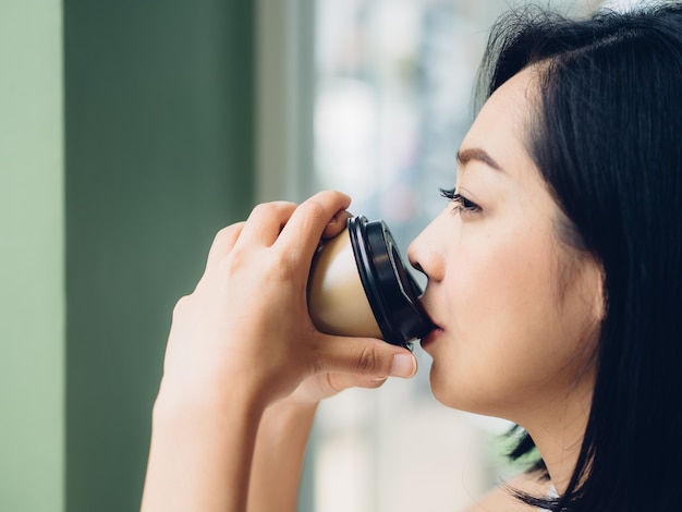 La donna sta bevendo una tazza di caffè caldo nel caffè.