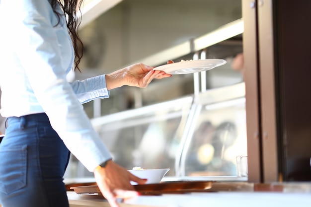 La donna sta con il vassoio e tiene il piatto della cena nelle sue mani