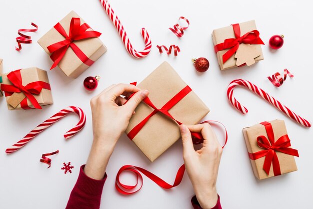 La donna sta confezionando un regalo a sorpresa per le vacanze di Natale seduta sul posto di lavoro con gli attrezzi artigianali vista superiore La donna sta avvolgendo il regalo di Natale al tavolo colorato