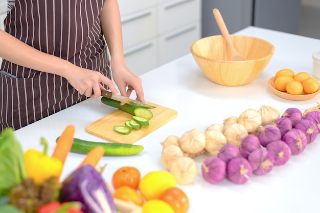 La donna sta cucinando nella cucina di casa. Le mani femminili tagliano le verdure, sul tavolo. donna che impara a fare un'insalata e cibo sano, resta a casa concetto.