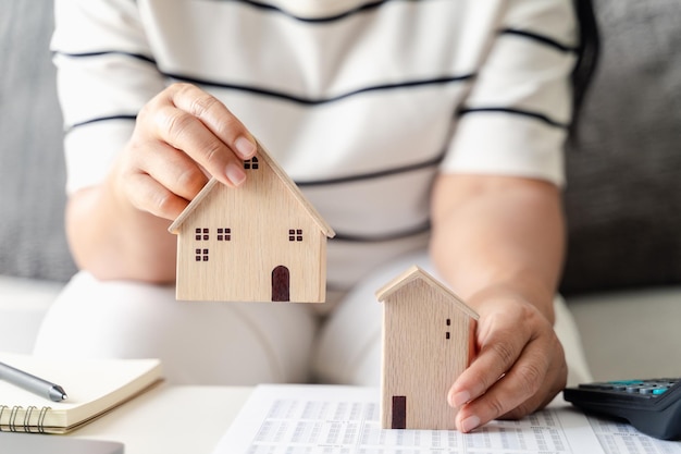 La donna sta decidendo di scegliere una casa con il modello di piccola casa in legno che pianifica di acquistare una proprietà