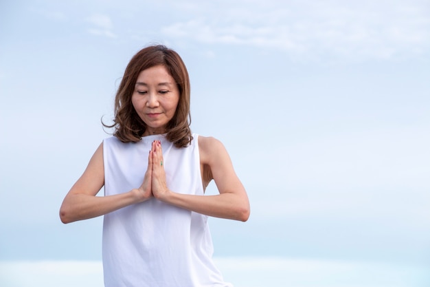 La donna sta facendo l&#39;yoga di esercizio su cielo blu