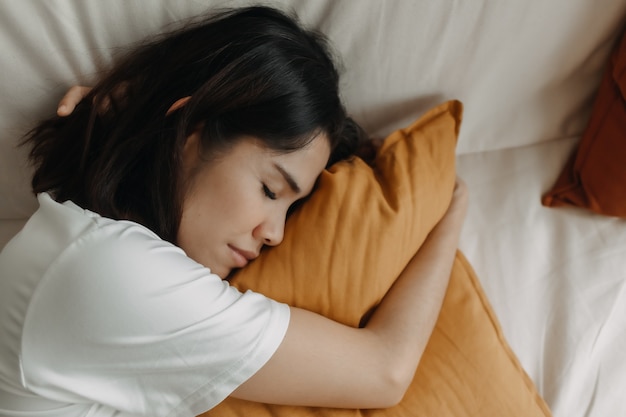 La donna sta facendo un pisolino o dorme sul divano con un cuscino giallo