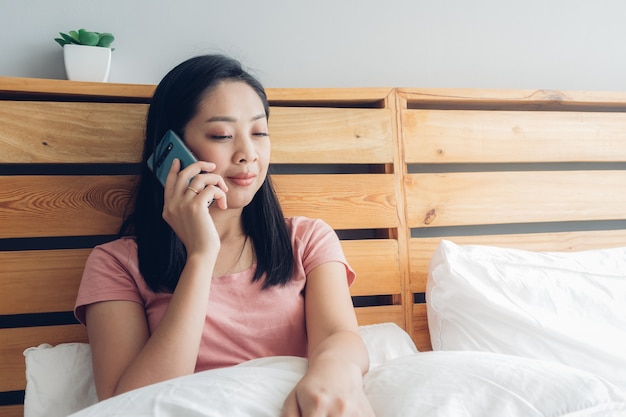 La donna sta facendo una conversazione telefonica sul suo letto la mattina.