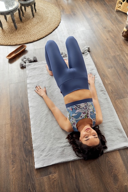 La donna sta facendo yoga e pratiche meditative nella stanza decorata in stile bali