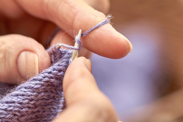 La donna sta lavorando a maglia un maglione caldo blu