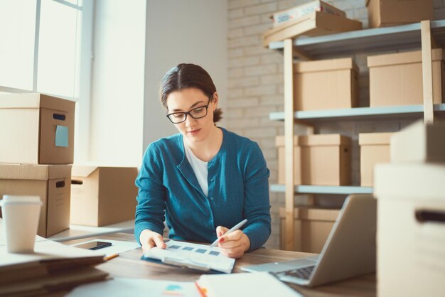 La donna sta lavorando al magazzino per il negozio online.