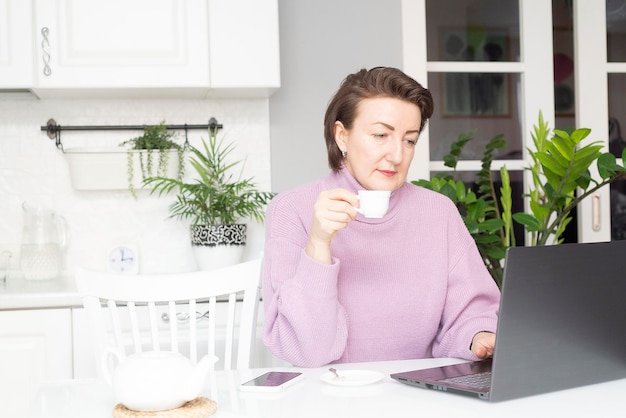 La donna sta lavorando con il laptop a casa online
