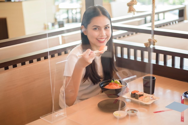 La donna sta mangiando nel ristorante con protocollo di allontanamento sociale mentre la città di blocco a causa della pandemia di coronavirus