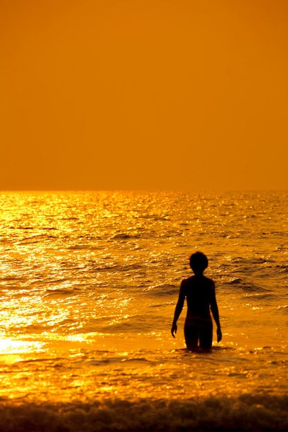 La donna sta nell'acqua sul mare e sul tramonto