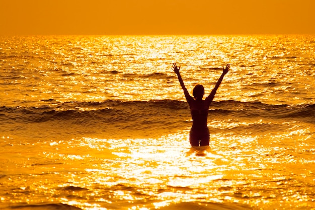 La donna sta nell'acqua sul mare e sul tramonto