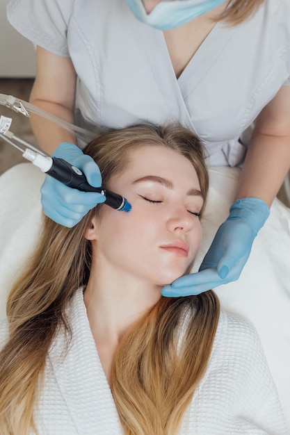 La donna sta ricevendo la pulizia sollevando il ringiovanimento idratando il trattamento del viso nella clinica di bellezza