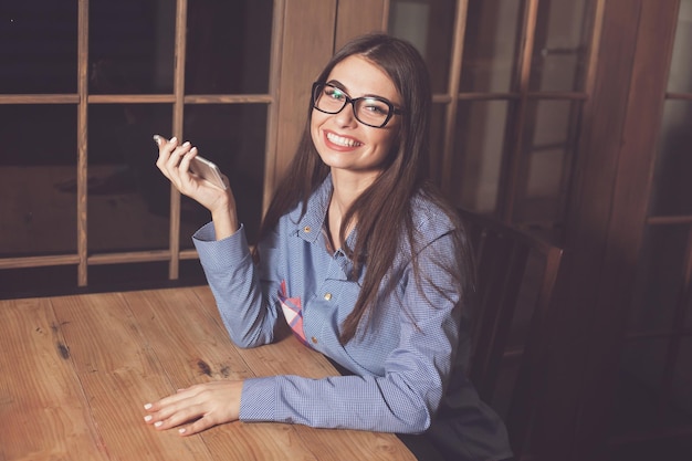 La donna sta sorridendo e si siede al tavolo con il telefono