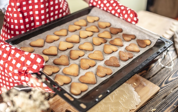 La donna sta tenendo tra le mani una teglia con deliziosi biscotti fatti in casa a forma di cuore