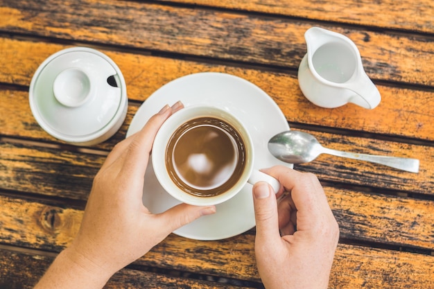 La donna sta tenendo una tazza di caffè in un caffè all'aperto