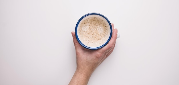 La donna sta tenendo una tazza di caffè su un tavolo bianco