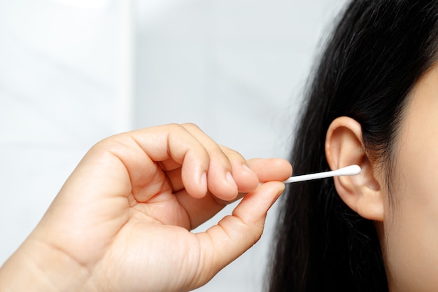 La donna sta usando i bastoncini di cotone puliscono un orecchio