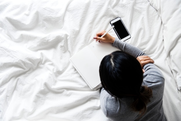 La donna sta usando il cellulare sul letto