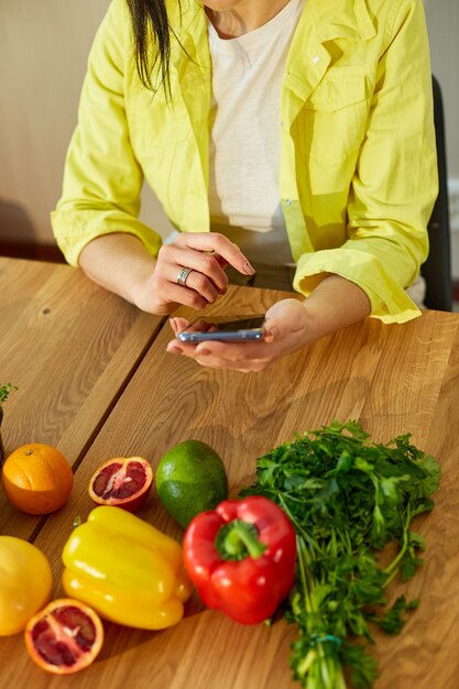 La donna sta usando lo smartphone, cercando la ricetta