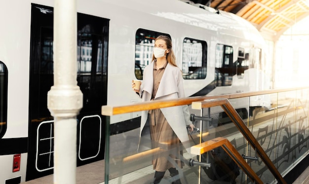 La donna sta viaggiando in treno durante la pandemia con la maschera facciale