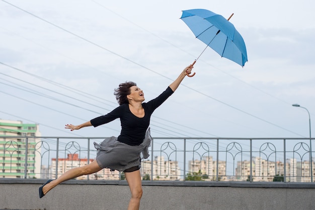 La donna sta volando con l'ombrello, tenendo l'ombrello, sfondo stile città.