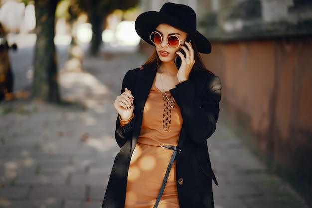 la donna styligh usa il suo cellulare mentre cammina per la città in una giornata soleggiata e calda