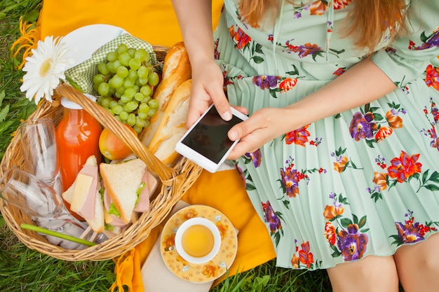 La donna sul picnic si siede sulla copertina gialla e tiene il telefono.