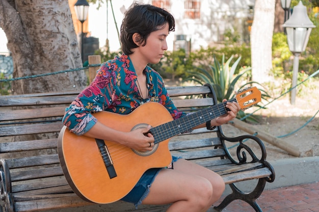 La donna suona la chitarra nel parco