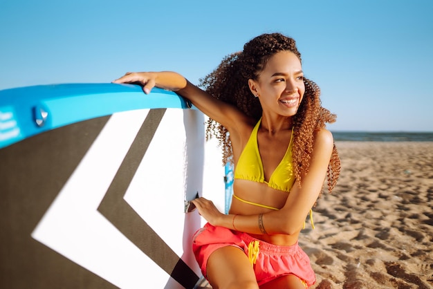 La donna surfista cammina con una tavola sulla spiaggia sabbiosa Sport estremi Viaggia lo stile di vita del fine settimana