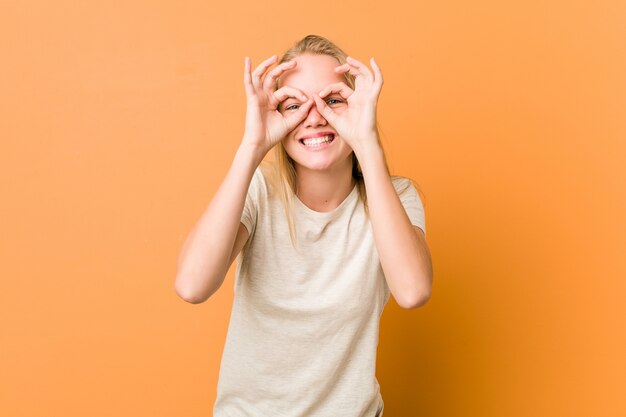 La donna sveglia e naturale dell'adolescente che mostra bene firma sopra gli occhi