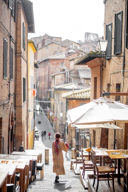 La donna Sylish cammina su una strada stretta e accogliente nel centro storico della città di Siena