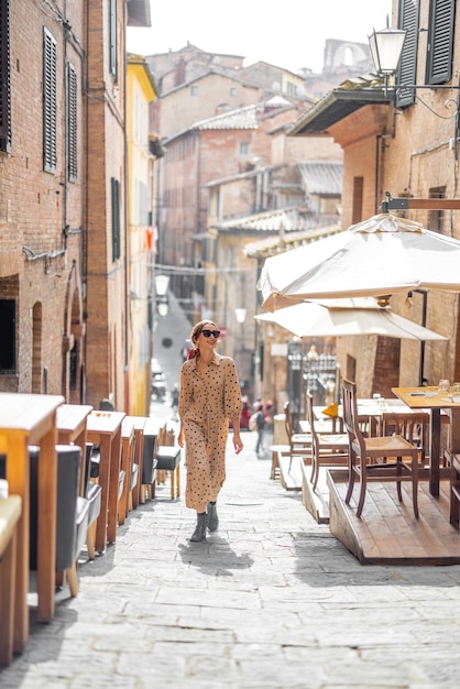 La donna Sylish cammina su una strada stretta e accogliente nel centro storico della città di Siena