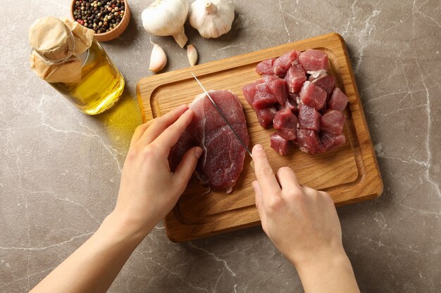 La donna taglia carne cruda bistecca su tavola di legno, vista dall'alto
