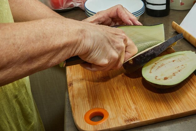 La donna taglia le melanzane per cucinare a casa usando la ricetta da Internet