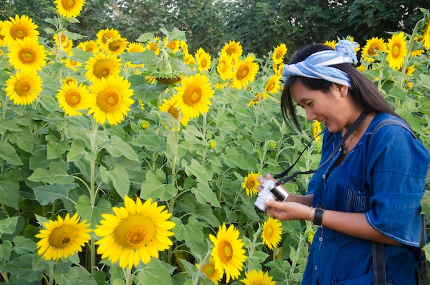 La donna tailandese asiatica usa il campo di fiori di girasole per scattare foto con la fotocamera per scrivere un blog al mattino a Saraburi Thailandia