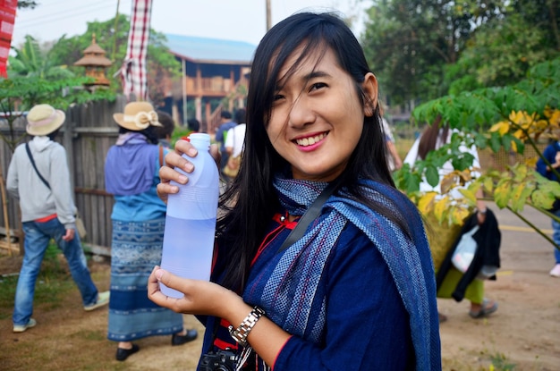 La donna tailandese sorride e tiene una bottiglia d'acqua per lo spettacolo al mattino a Ban Non Hom a Sakon Nakhon Thailandia